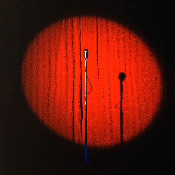 spotlight on a mic sitting on a stand in front of a velvet curtain